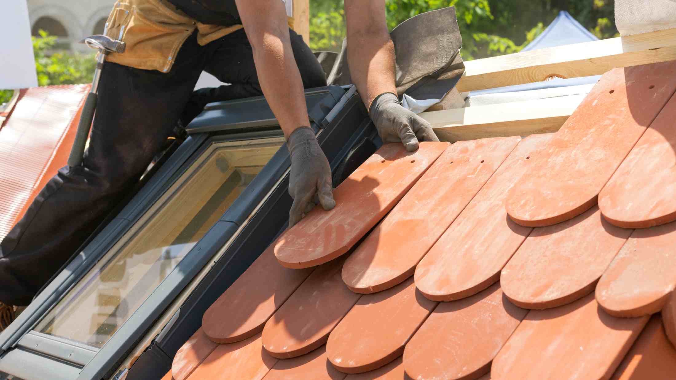 Hands of roofer laying tiles on the roof