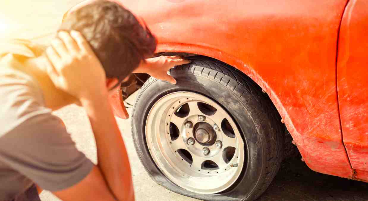 Man looking at a punctured tyre